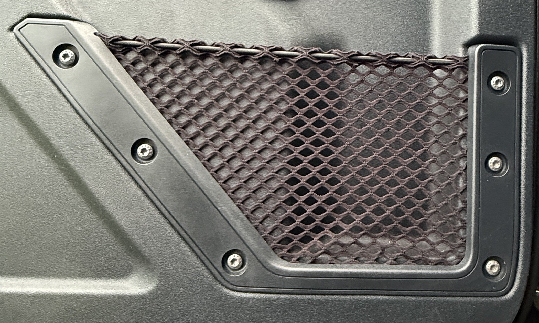 Detailed view of a replacement mesh storage net securely installed using the original mounting spots on a Bronco door panel.