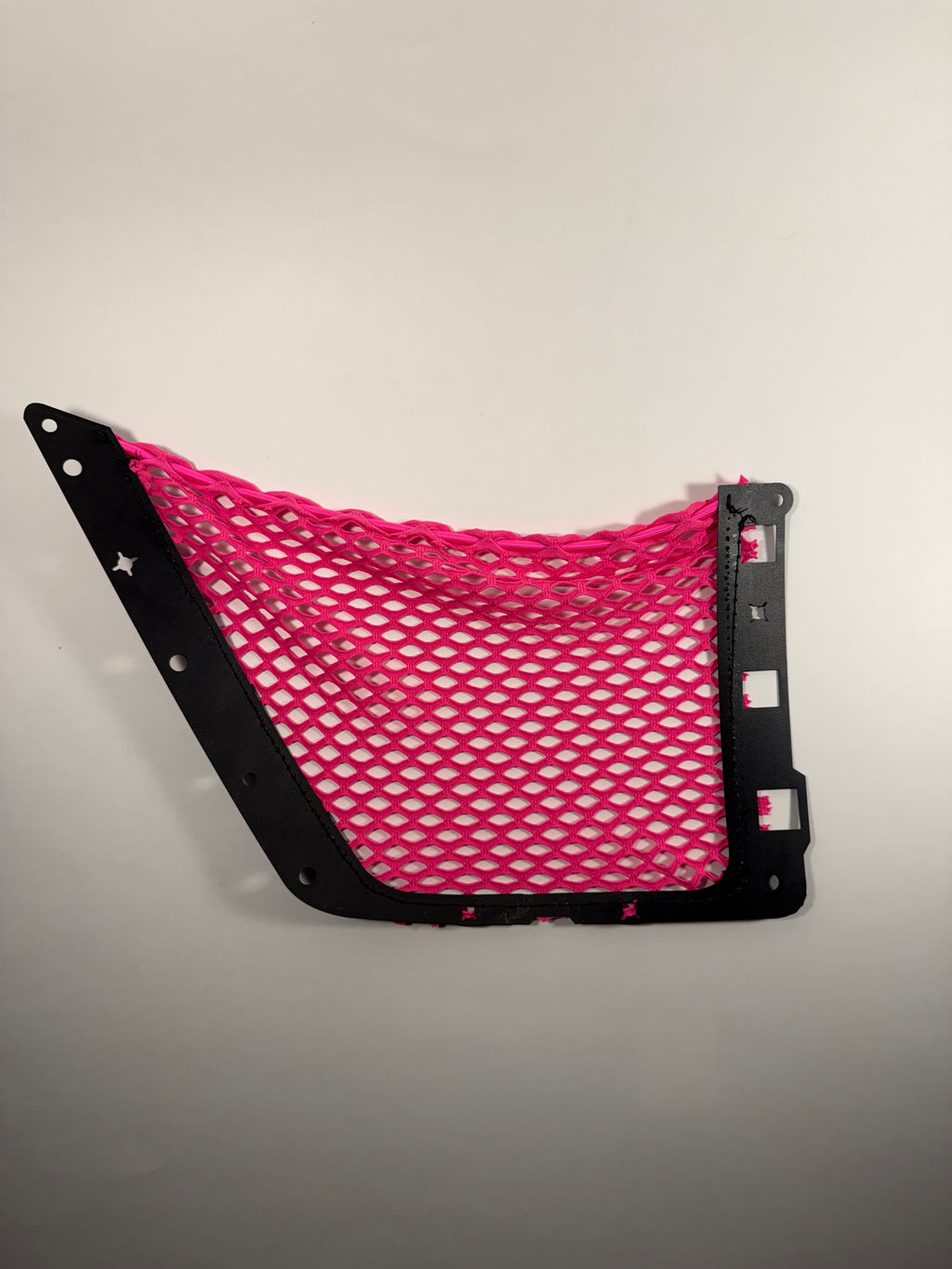 The back side of a bright pink mesh cargo net with black plastic mounting brackets, shown against a plain light background.